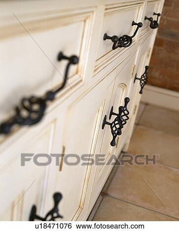 Stock Photograph - Close-up of cream kitchen units with metal handles. Fotosearch