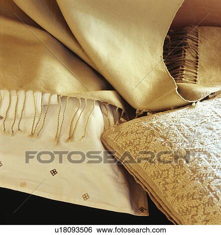 Stock Photograph - Close-up of cream pashmina scarf on textured cream cushions. Fotosearch