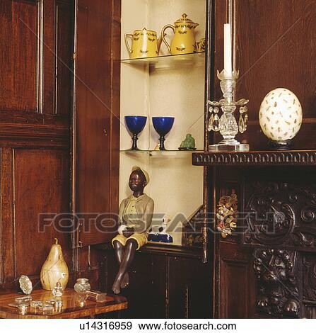 Stock Photo - Close-up of cupboard door open to shelves with antique china and blackamoor figure. Fotosearch