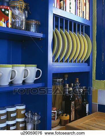 Stock Photograph - Close-up of cups and plates on bright blue shelves. Fotosearch