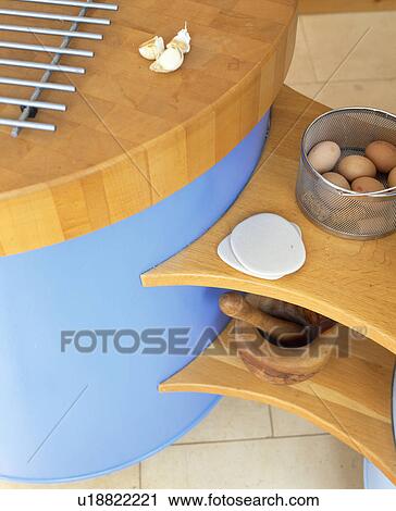 Stock Image - Close-up of curved blue kitchen unit with wooden worktop and shelves. Fotosearch