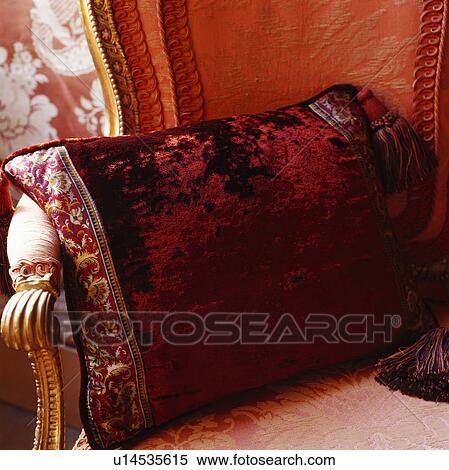 Stock Photography - Close-up of dark red velvet cushions on antique brocade-covered chair. Fotosearch