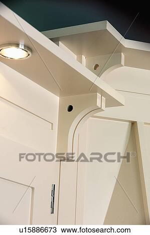 Stock Image - Close-up of downlighting below white shelf. Fotosearch