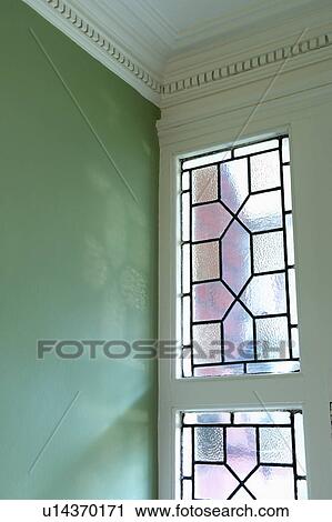 Stock Image - Close-up of Edwardian stained-glass window in green hall. Fotosearch