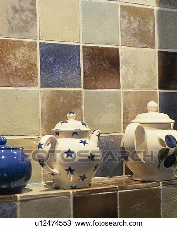 Stock Image - Close-up of Emma Bridgewater star motif teapot against tiled wall. Fotosearch