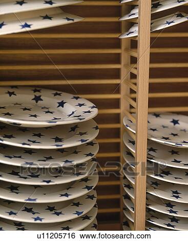 Stock Photograph - Close-up of Emma Bridgewater star motif plates in wooden plate rack. Fotosearch