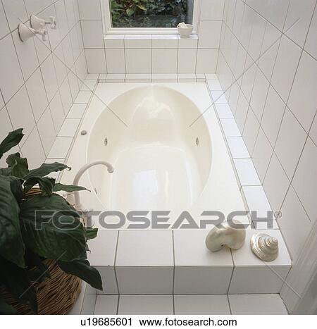 Stock Image - Close-up of fitted bath in modern white tiled bathroom. Fotosearch