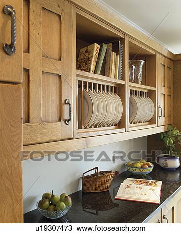 Stock Image - Close-up of fitted oak kichen cupboard with integral plate rack. Fotosearch