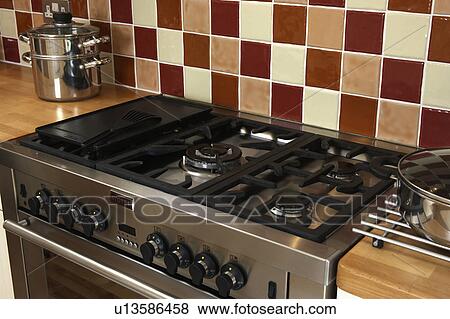 Close-up of gas hob on stainless steel range oven below brown and cream tiled wall View Large Photo Image Stock Photo - Close-up of gas hob on stainless steel range oven below brown and cream tiled wall. Fotosearch