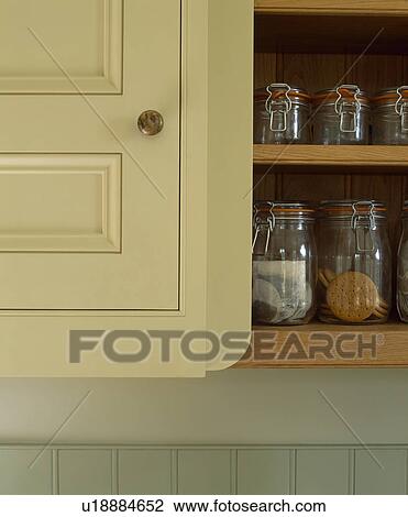 Stock Image - Close-up of glass storage jars in cream cupboard. Fotosearch