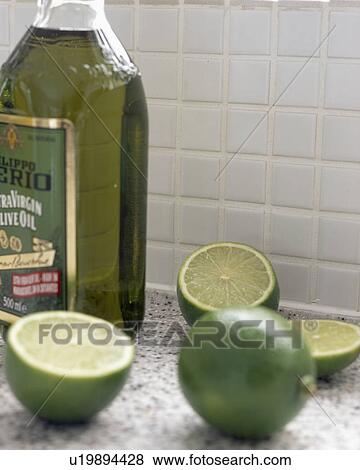 Stock Photo - Close-up of halved limes on worktop with bottle of olive oil. Fotosearch