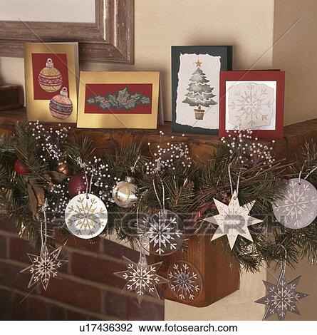 Stock Image - Close-up of hand-made stencilled Christmas cards on mantelpiece with home-made stencilled decorations. Fotosearch