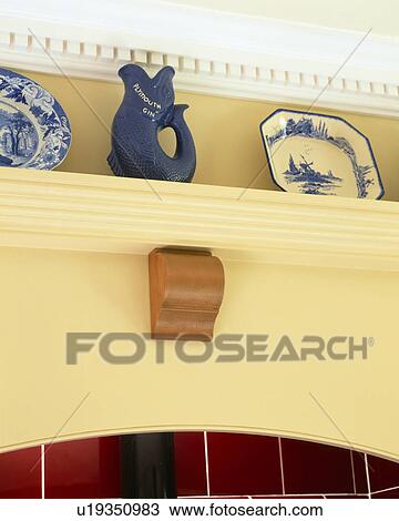 Stock Image - Close-up of jug and blue plates on cream kitchen shelf. Fotosearch