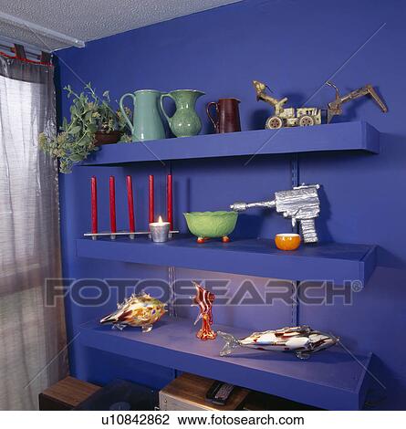Stock Image - Close-up of jugs and ornaments on bright blue shelves. Fotosearch