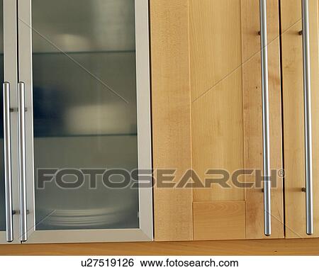 Stock Photograph - Close-up of kitchen cupboard with glazed door and long brushed-steel handles. Fotosearch