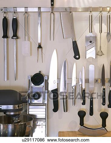 Stock Photograph - Close-up of kitchen knives and steel utensils on metal rack. Fotosearch