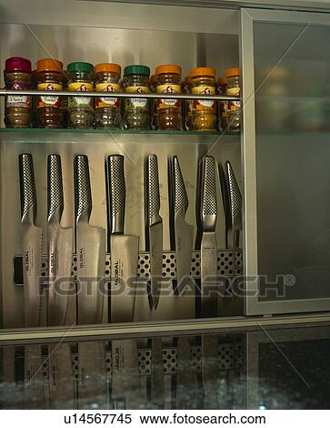Stock Photography - Close-up of kitchen knives stored on rack below herb and spice jars. Fotosearch