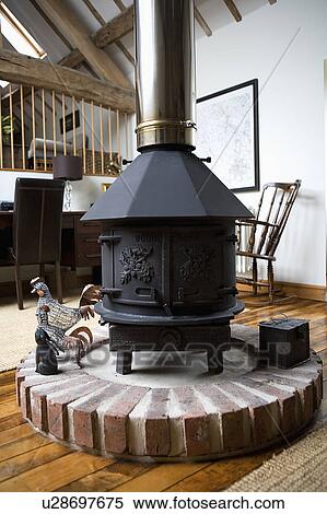 Close up of large black cast iron stove on raised brick plinth in centre of open plan living room View Large Photo Image Stock Photography - Close up of large black cast iron stove on raised brick plinth in centre of open plan living room. Fotosearch
