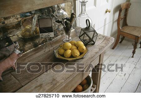 Stock Image - Close-up of lemons in ceramic dish on old wooden table with silvered mirror. Fotosearch
