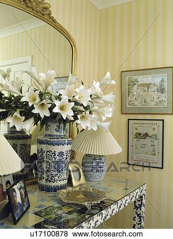 Stock Photo - Close-up of lilies in blue+white vase on console table. Fotosearch