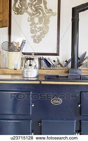 Stock Photo - Close-up of metal kettle on blue Nobel oven. Fotosearch