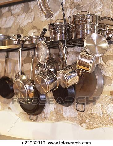 Stock Photo - Close-up of metal pans hanging from wall-shelf. Fotosearch