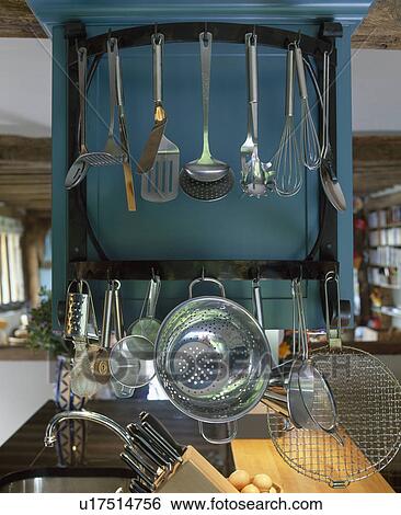 Stock Photograph - Close-up of metal utensils and colander on blue kitchen storage rack. Fotosearch