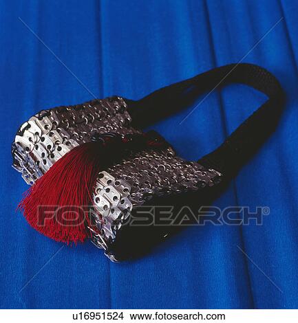 Close-up of metallic chain handbag with red tassel on blue background View Large Photo Image Picture - Close-up of metallic chain handbag with red tassel on blue background. Fotosearch