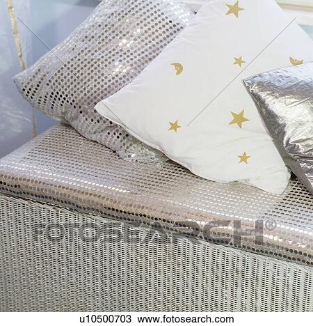 Stock Image - Close-up of metallic cushions on wicker chest. Fotosearch