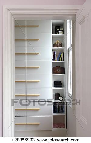 Stock Image - Close-up of narrow shelves beside fitted wardrobe. Fotosearch