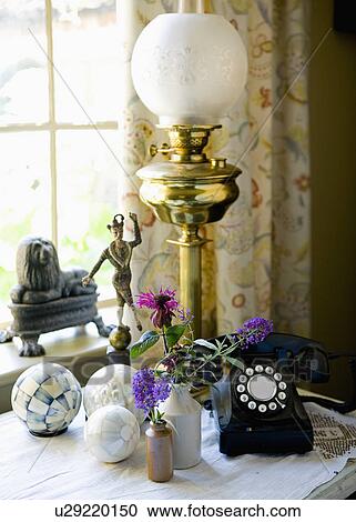 Stock Image - Close-up of of Victorian brass lamp and old black telephone on table with marble balls. Fotosearch