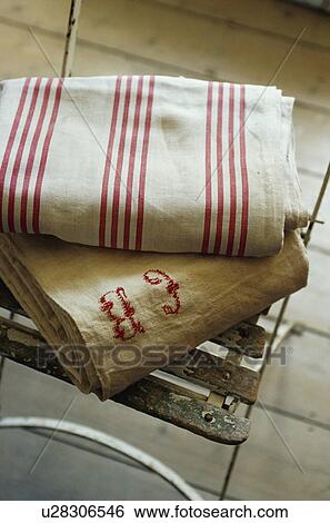 Stock Photograph - Close-up of old rough linen French sheets on metal stool. Fotosearch