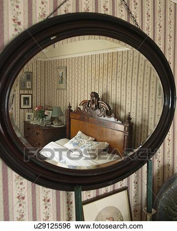 Close-up of oval mahogany-framed mirror with reflection of old-fashioned country bedroom View Large Photo Image Stock Photograph - Close-up of oval mahogany-framed mirror with reflection of old-fashioned country bedroom. Fotosearch