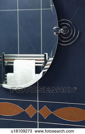 Stock Image - Close-up of oval mirror on tiled wall. Fotosearch