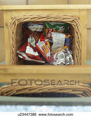 Stock Photograph - Close-up of packets of crisps in wicker storage basket. Fotosearch