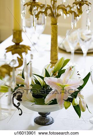 Stock Image - Close-up of pale pink lilies in stemmed glass bowl. Fotosearch