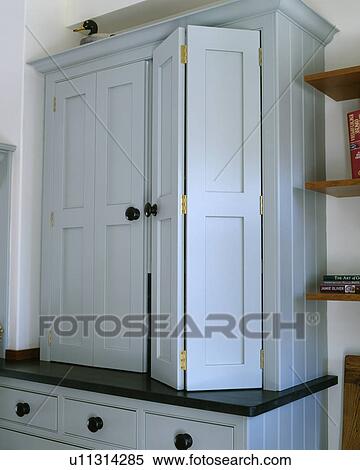 Stock Photography - Close-up of pastel blue fitted kitchen cupboard with folding door. Fotosearch