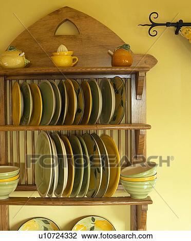 Stock Image - Close-up of pastel plates and bowls on wooden plate rack. Fotosearch