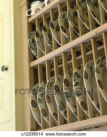 Picture - Close-up of patterned pottery plates on fitted wooden plate rack. Fotosearch