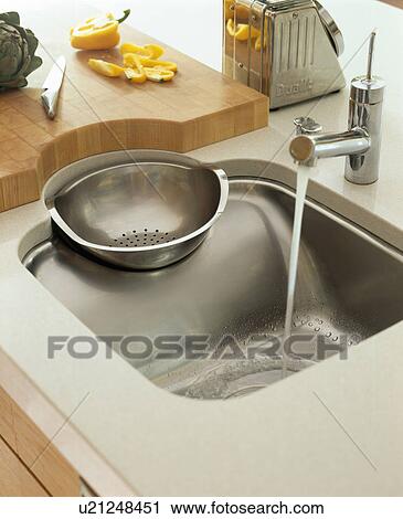 Stock Image - Close-up of Philippe Starck stainless steel sink and drainer with Franke tap. Fotosearch