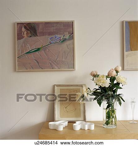 Picture - Close-up of pictures above console table with small framed drawing and pink and white paeonies in glass vase&#10; &#10; &#10; &#10; &#10; &#10; &#10; &#10; &#10; &#10; &#10; &#10;. Fotosearch