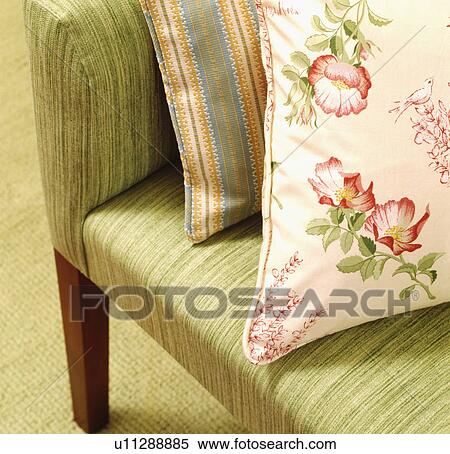 Stock Photography - Close-up of pink floral cushion on green armchair. Fotosearch