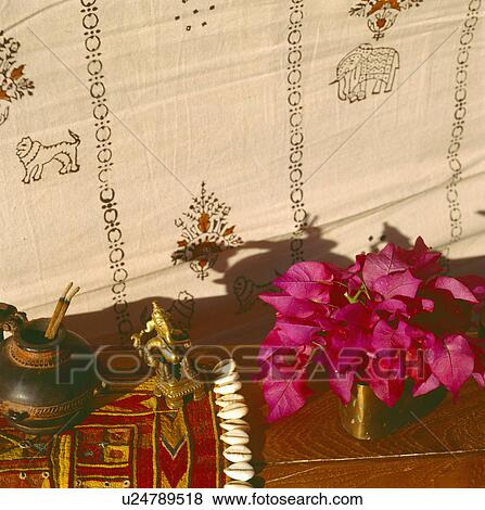 Stock Photo - Close-up of pink rhododendrons in vase on wooden table with Rajastani embroidered cloth. Fotosearch
