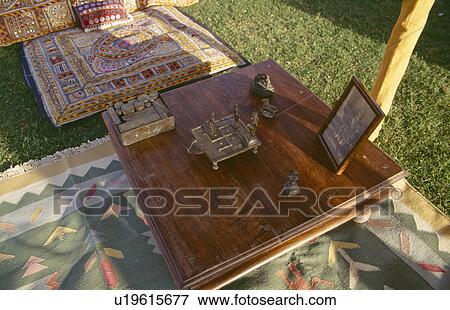Stock Photo - Close-up of Rajastani brass ornaments on wooden table in tent. Fotosearch