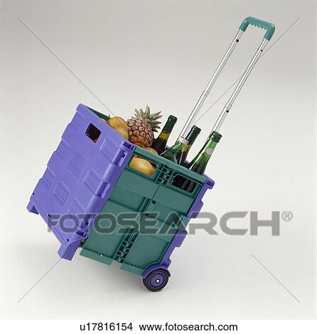 Picture - Close-up of red and green plastic shopping trolley with wine and fruit. Fotosearch