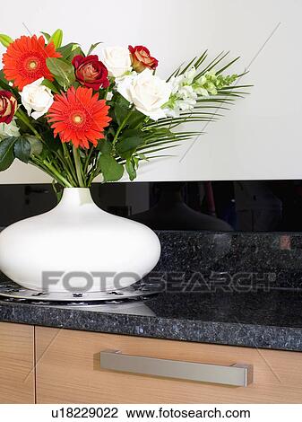 Stock Image - Close-up of red and white flowers in white vase. Fotosearch