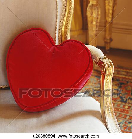 Picture - Close-up of red heart-shaped cushion on gilt-framed chair. Fotosearch