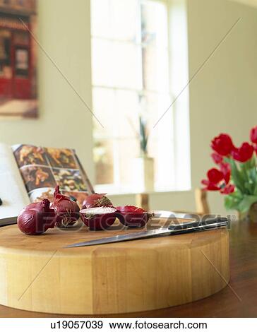 Stock Photo - Close-up of red onions and large knife on wooden kitchen worktop. Fotosearch