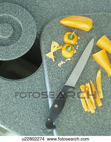 Picture - Close-up of sharp kitchen knife and slices of yellow pepper on worktop. Fotosearch