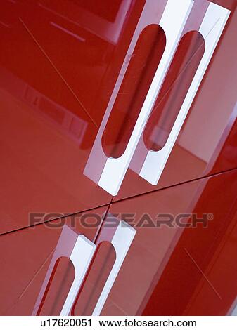 Stock Image - Close-up of shiny red storage cupboard with white handles. Fotosearch